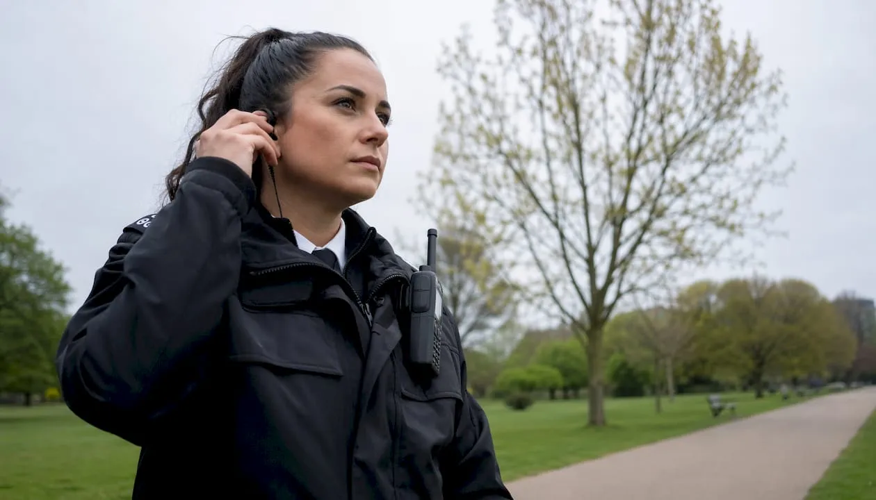 UK female security guard outdoors adjusting radio
